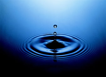 Blue water droplet splash with ripples on dark background
