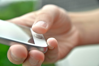 Close-up of hand pressing smartphone home button