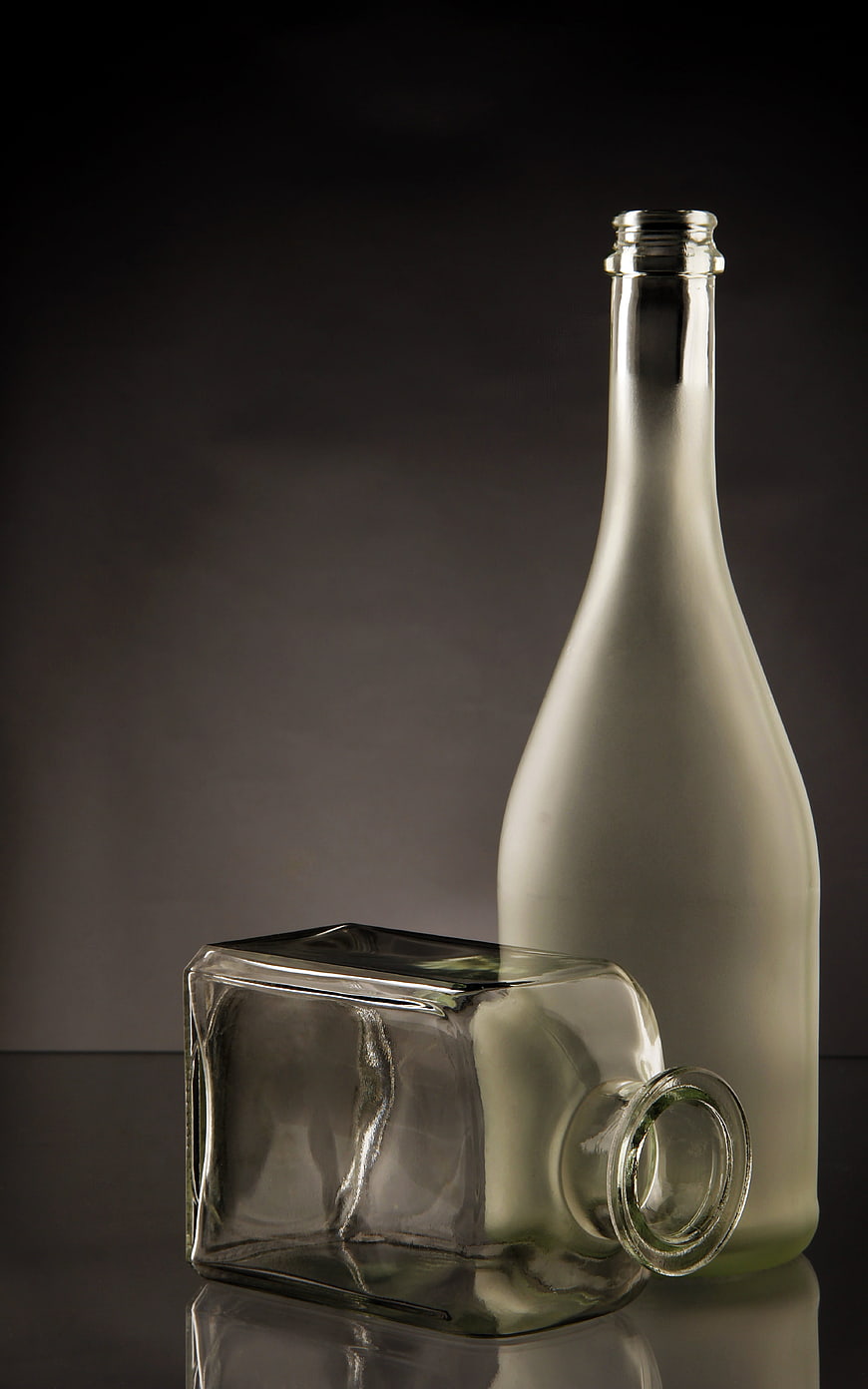 Empty frosted and clear glass bottles on dark background