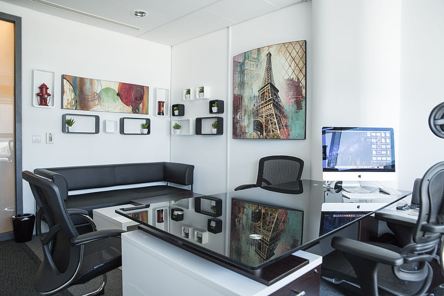 Modern serviced office interior with glass desk and artwork