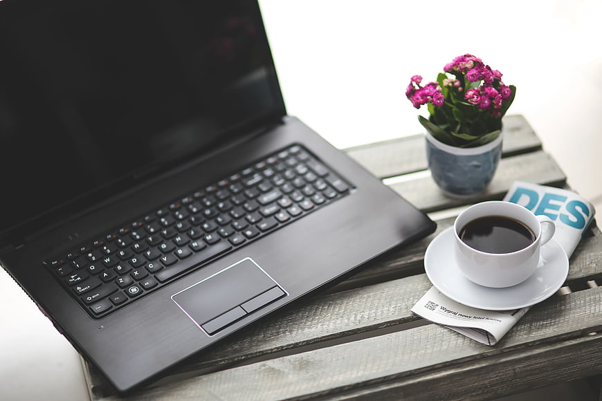 Laptop, coffee, and flowers on rustic wooden table