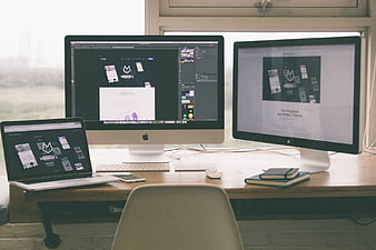 Modern workspace with dual monitors and laptop displaying web design