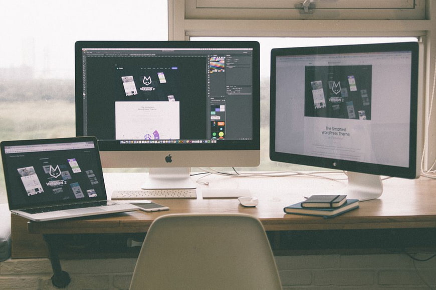 Modern workspace with dual monitors and laptop displaying web design