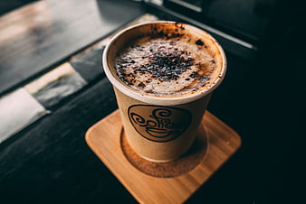 Top View of Frothy Cappuccino in Paper Cup on Wooden Coaster