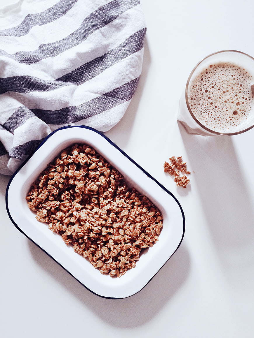 Overhead view of granola in white dish with oat milk