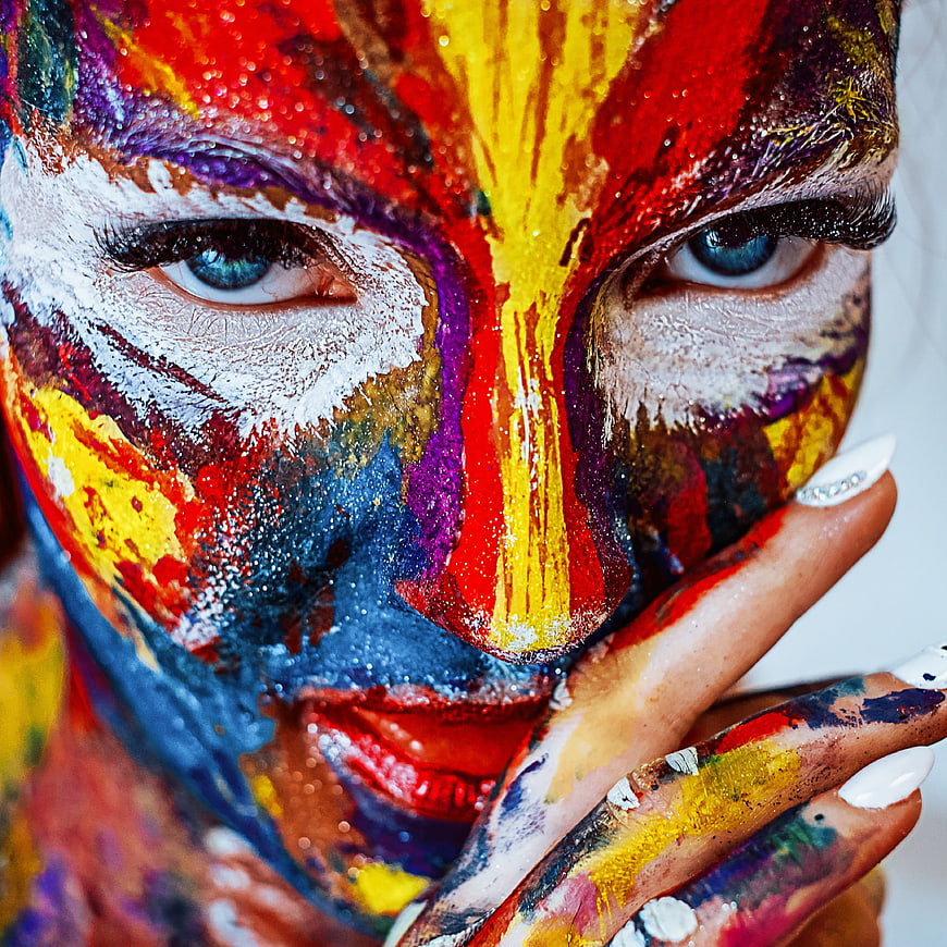 Close-up portrait of woman with vibrant multicolor face paint