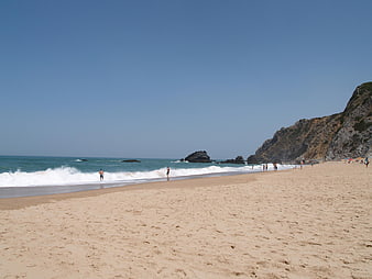 Sandy Beach with Ocean Waves and Rocky Cliffs