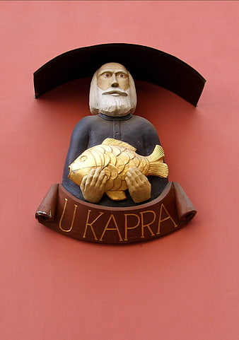 U Kapra Fisherman Statue on Red Wall in Prague