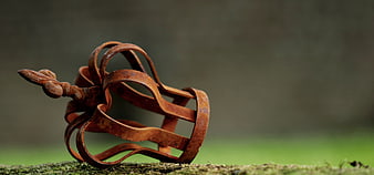 Rusty metal crown sculpture on mossy surface