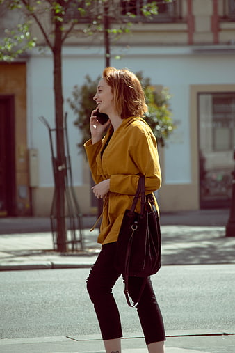 Happy woman walking and talking on smartphone in city