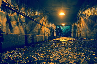 Low angle view of graffiti tunnel with water and silhouettes