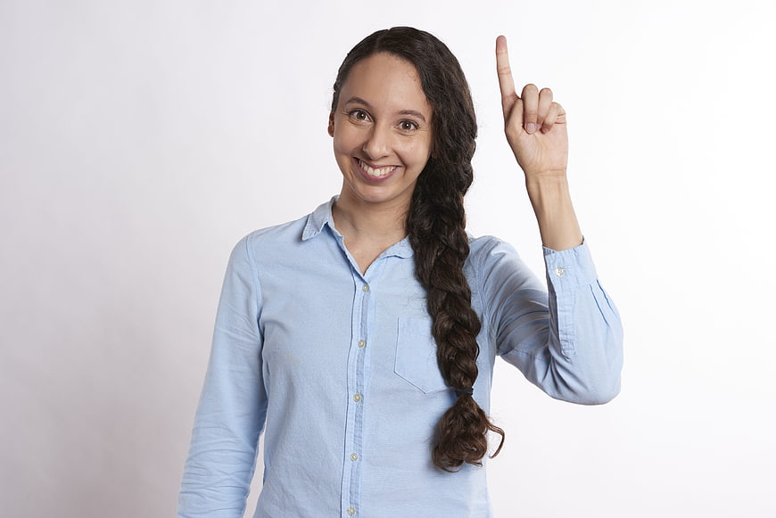 Smiling woman with braid pointing finger upward on white background