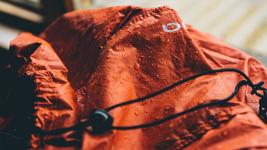 Close-up of wet orange rain jacket with water droplets