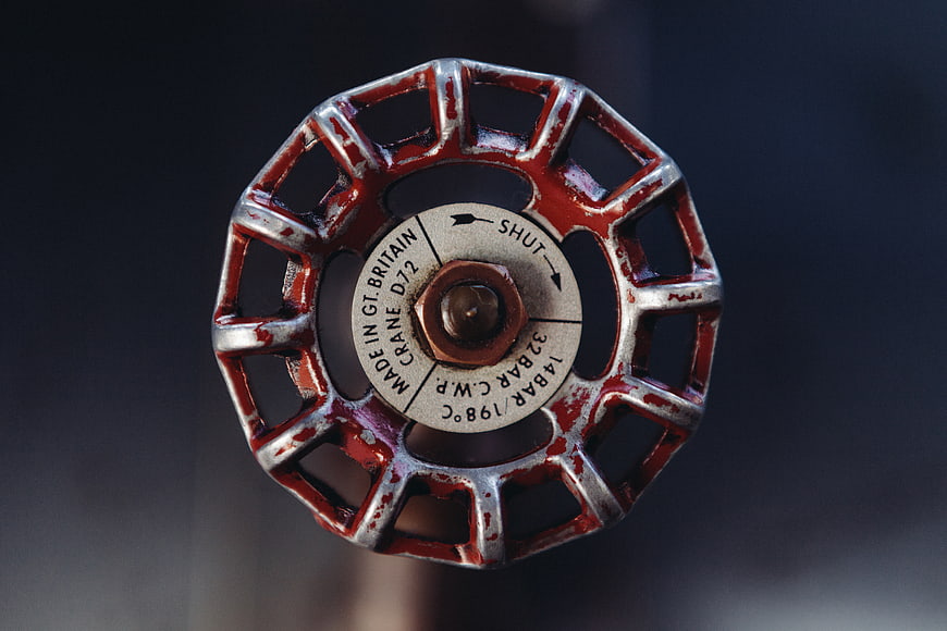 Close-up of vintage red industrial valve wheel with text