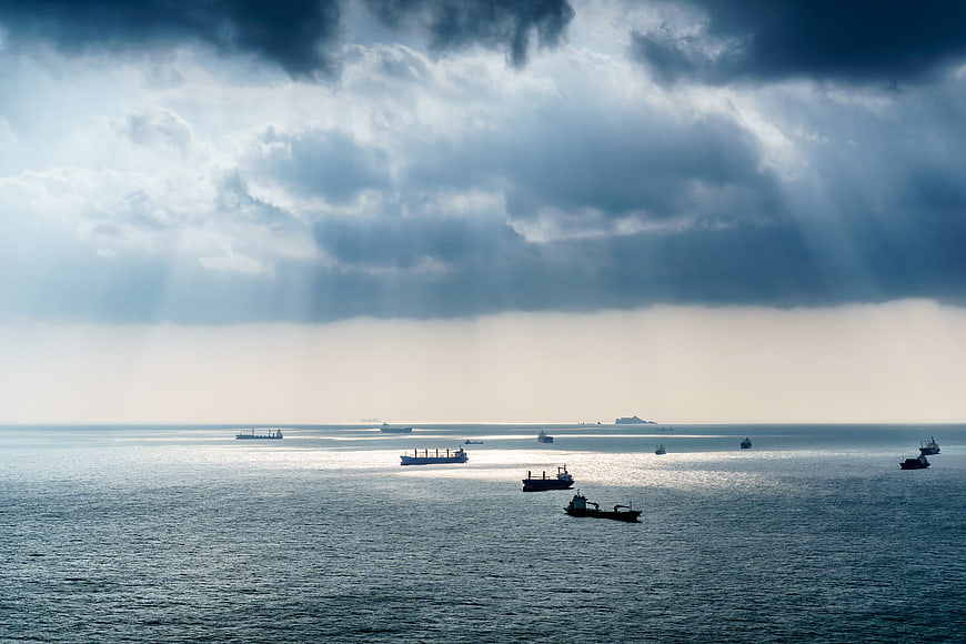 Cargo Ships Anchored in Ocean Under Dramatic Stormy Sky