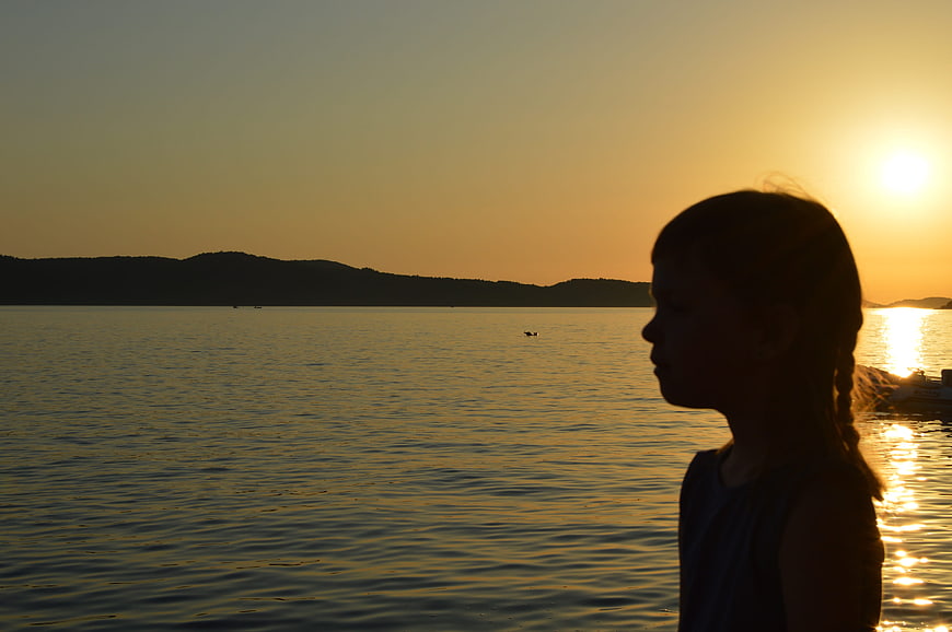 Silhouette of Girl Watching Sunset Over Calm Sea