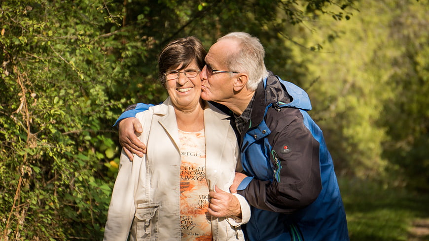Senior couple sharing a kiss outdoors in a natural green setting