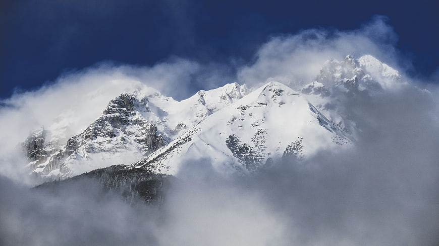 Snowy Mountain Peaks Emerging Through Thick Clouds