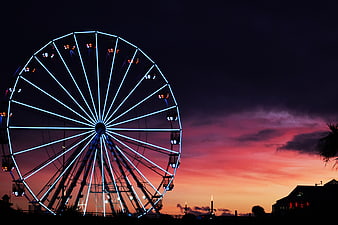 Illuminated Ferris Wheel Silhouette Against Vibrant Sunset Sky