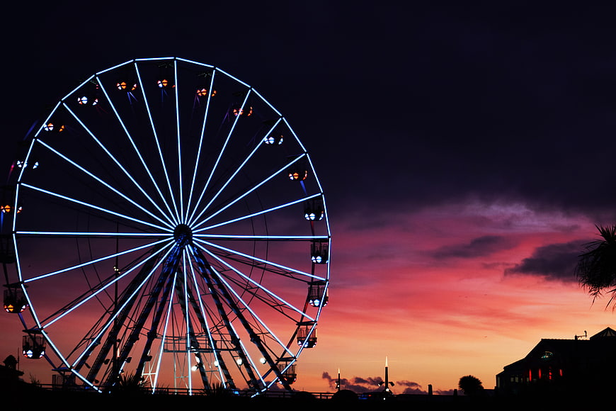 Illuminated Ferris Wheel Silhouette Against Vibrant Sunset Sky