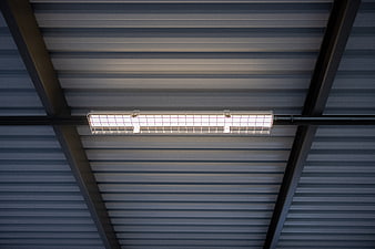 Industrial fluorescent light fixture on corrugated metal ceiling