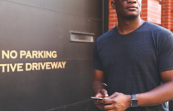 African American Man Texting Smartphone Near Garage Door