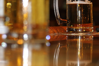 Close-up of beer mug on wooden bar with reflection