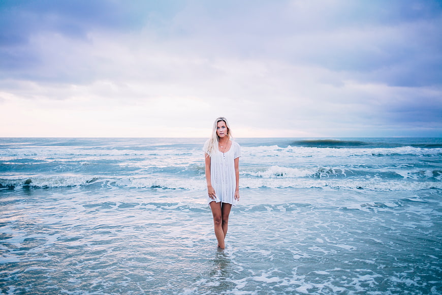 Blonde Woman in White Dress Standing in Ocean Waves