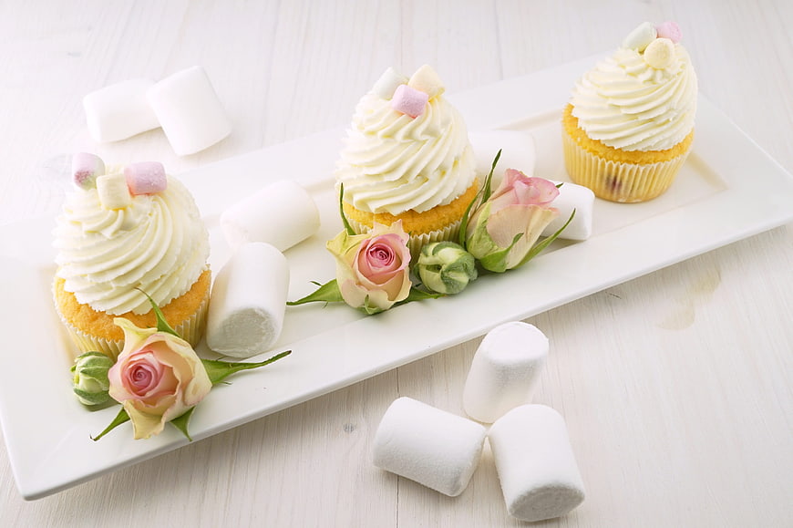 Vanilla cupcakes with marshmallows and roses on white plate