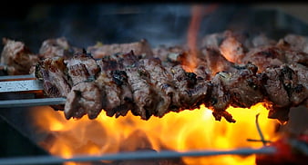 Grilled meat skewers cooking over open flames on a barbecue grill