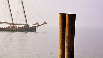 Wooden mooring post with sailing ship in background