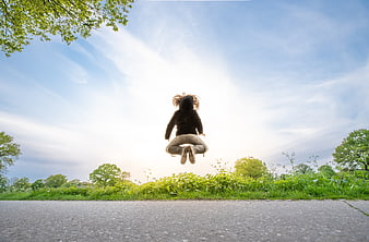 Woman jumping in the air outdoors with blue sky background