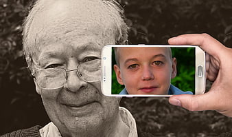 Senior man portrait with smartphone displaying young boy face
