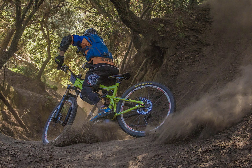 Mountain biker kicking up dust on forest trail