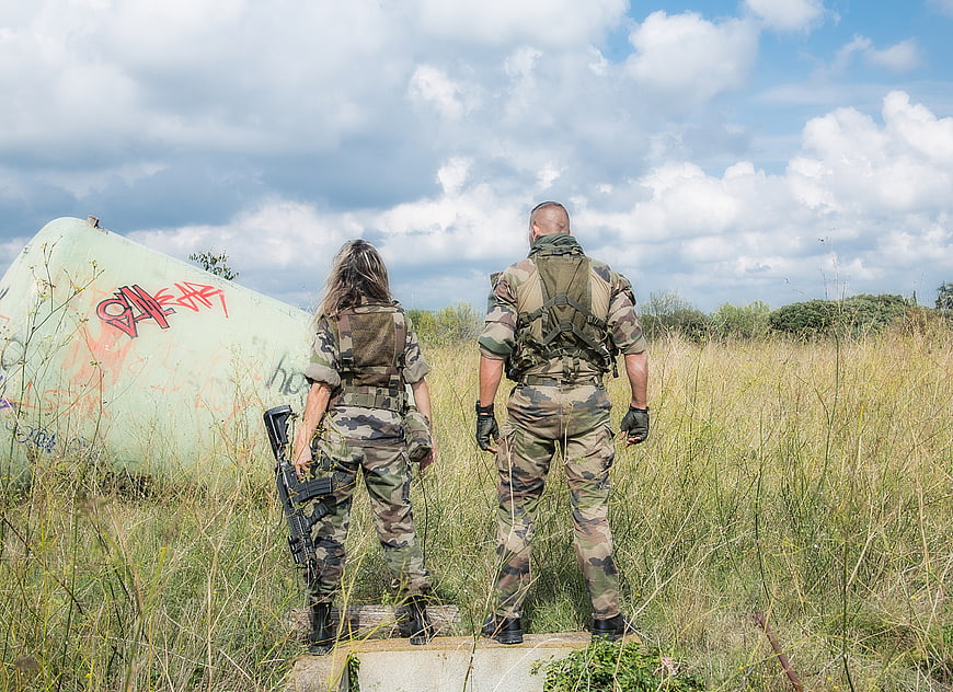 Soldiers in camouflage standing in a field with a crashed plane