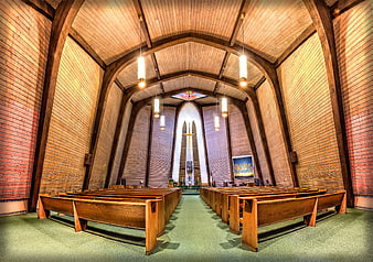 Interior of a modern brick chapel with wooden pews and arched ceiling