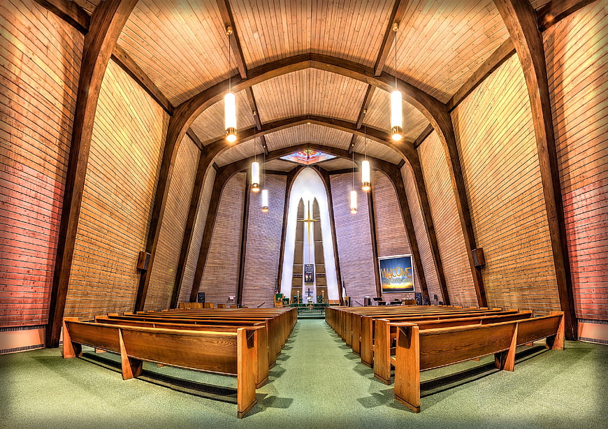 Interior of a modern brick chapel with wooden pews and arched ceiling