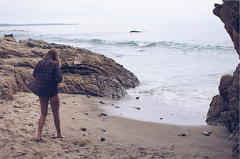Woman in Plaid Shirt Standing on Rocky Beach