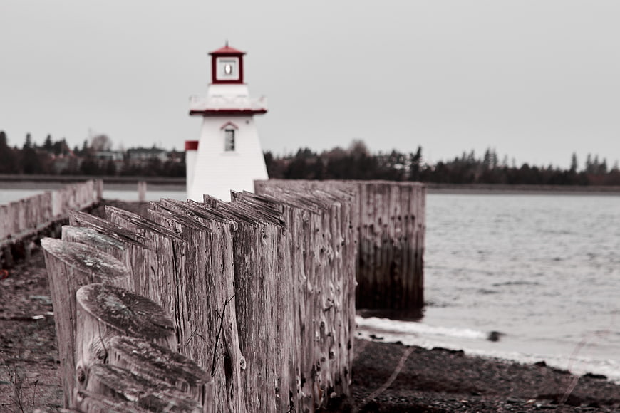 Weathered Wooden Seawall with Blurred Lighthouse Background