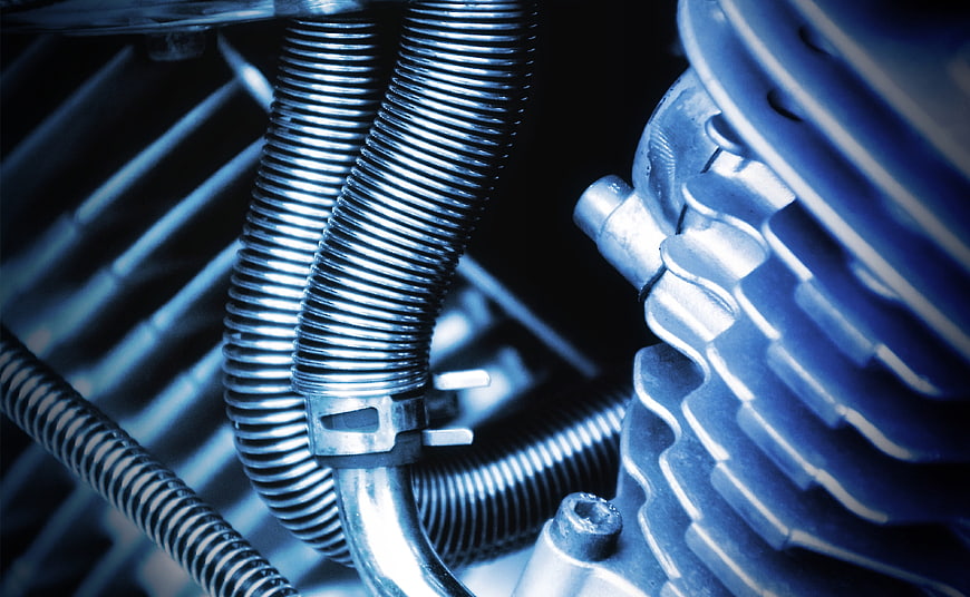 Close-up of motorcycle engine cooling fins and hoses