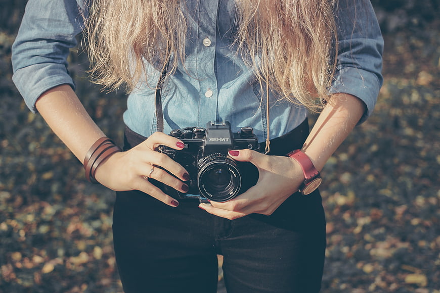 Woman holding vintage camera in autumn park