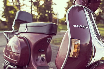 Close-up of a vintage maroon Vespa scooter in a park