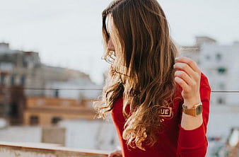 Woman in Red Sweater Touching Hair on Balcony