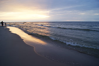 Serene Baltic Sea Sunset with Silhouetted Figures on Sandy Beach