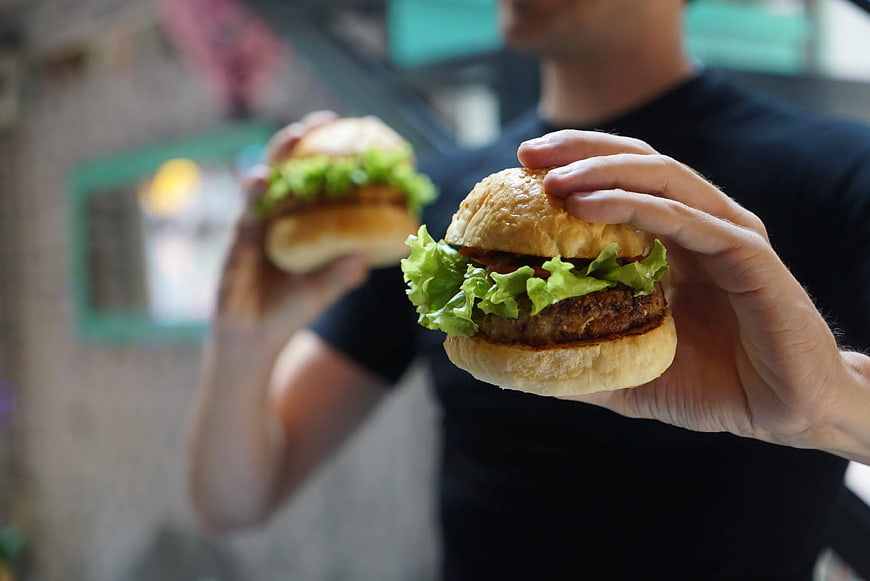 Man Holding Two Fresh Burgers with Lettuce