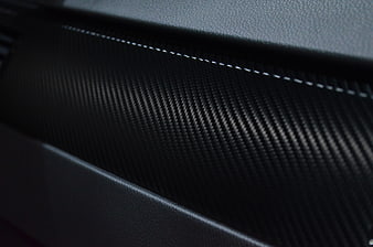 Close-up of black carbon fiber texture with white stitching