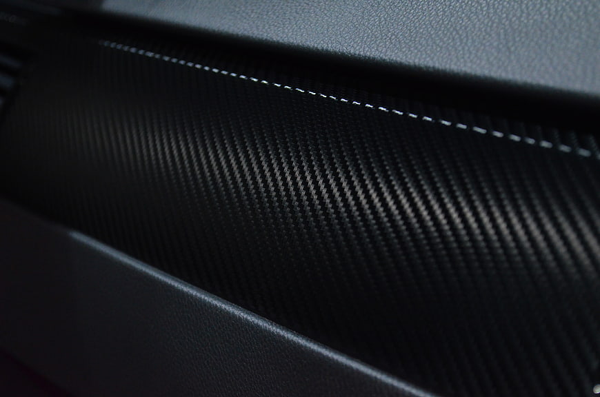 Close-up of black carbon fiber texture with white stitching
