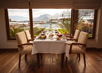 Romantic dinner table set with wine overlooking marina and mountains