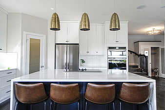 Modern White Kitchen With Marble Island And Gold Pendant Lights