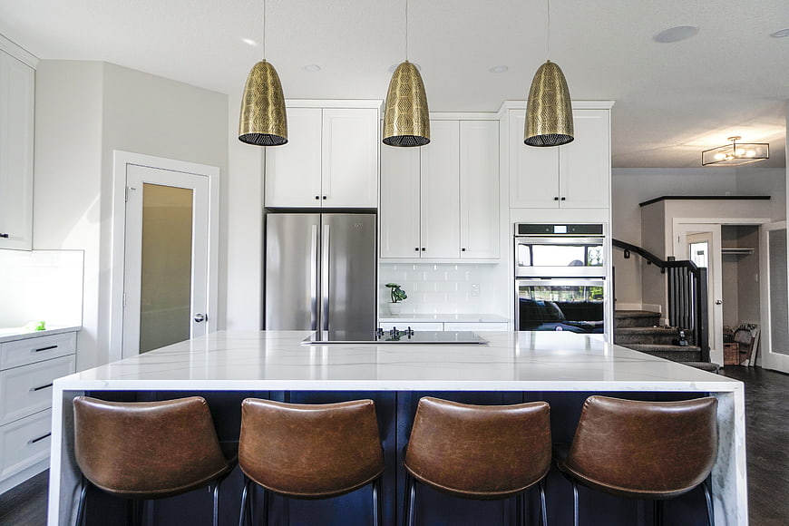 Modern White Kitchen With Marble Island And Gold Pendant Lights